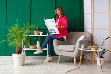 Evdeki koltukta oturan gazeteli genç ve güzel bir kadın.