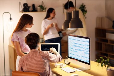 Genç programcılar geceleri ofiste dizüstü bilgisayarla çalışıyorlar.