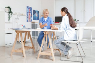 Kadın endokrinolog, tiroit bezini klinikteki hastaya gösteriyor.