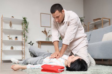 Genç adam evde kalp krizi geçiren baygın eşine kalp masajı yapıyor.