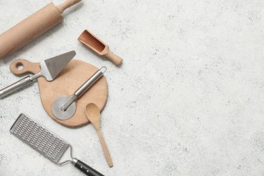 Paslanmaz çelik pizza kesicisi ve arka planda farklı mutfak aletleri olan kompozisyon.