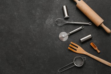 Arka planda paslanmaz çelik pizza keskisi olan farklı mutfak aletleri.