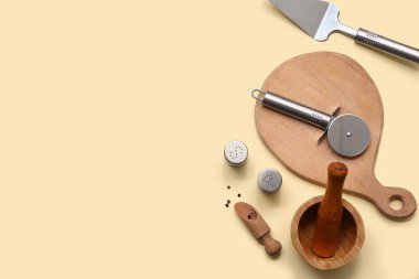 Renkli arka planda paslanmaz çelik pizza kesicisi, mutfak gereçleri ve baharatları olan kompozisyon