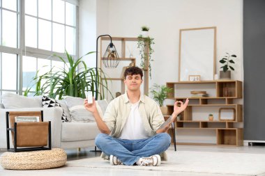 Klimalı yakışıklı genç adam evde meditasyon yapıyor.