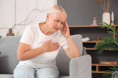 Olgun bir kadın evdeki koltukta kalp krizi geçiriyor.