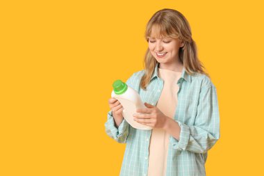 Sarı arka planda çamaşır deterjanı tasviri okuyan genç bir kadın.