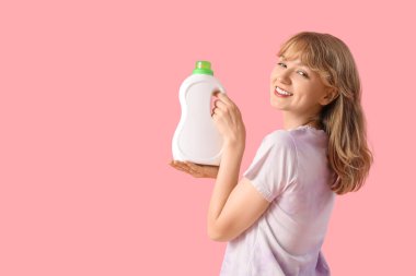 Pembe arka planda çamaşır deterjanı olan genç bir kadın.