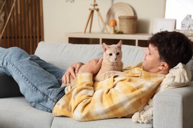Sonbahar günü evde tatlı kedisi olan genç bir adam yatıyor.