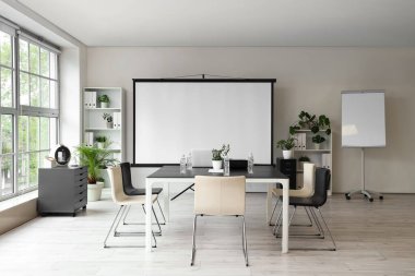 Projektör ekranı ve toplantı tablosu olan ofis içi