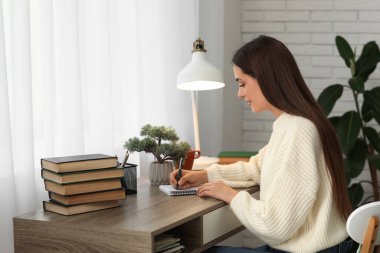 Masada kitap yığınıyla ders çalışan güzel mutlu kız öğrenci.