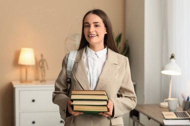 Evinde kitap ve sırt çantasıyla güzel, mutlu bir kız öğrenci.