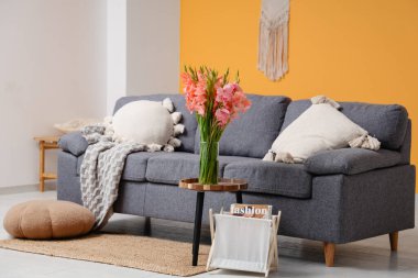 Kanepe ve vazoda gladyatör çiçekleri olan şık bir oturma odası.