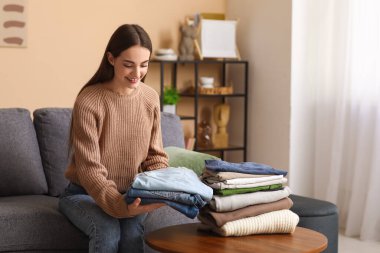 Genç kadın katlanmış kotu evdeki masaya koyuyor.