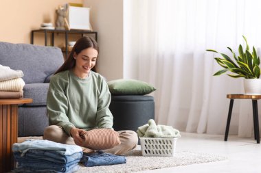 Genç bir kadın evde giysileri katlıyor.