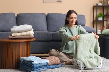Genç bir kadın sıcak süveterini evde katlıyor.