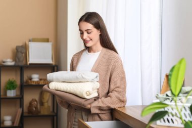 Evde bir yığın elbisesi olan genç bir kadın.