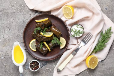 Lezzetli Dolmas (doldurulmuş üzüm yaprakları), ekşi krema, yağ, baharat ve arkaplanda limon kompozisyonu