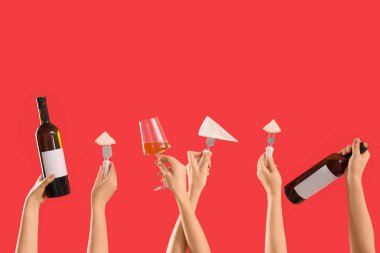 Kırmızı arka planda peynir, şişe ve şarap tutan kadın elleri