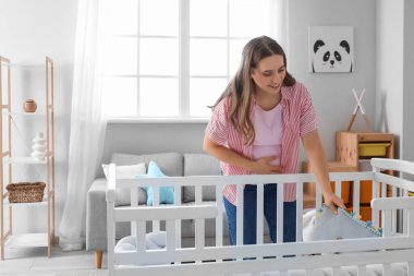 Taşındığı gün çocuk odasında yastığını ayarlayan hamile bir kadın.