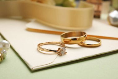 Nişan ve evlilik yüzükleri yeşil arkaplanlı, yakın plan.