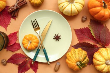 Taze balkabakları, meşe palamutları, yıldız anasonu, tarçın ve sonbahar yapraklarıyla turuncu arka planda güzel bir masa.