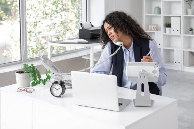 Genç Afro-Amerikalı iş kadını telefonla konuşuyor ve son teslim tarihine yetişmeye çalışıyor.