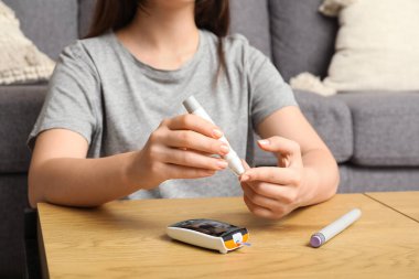 Şeker hastası genç bir kadın evde tükenmez kalem kullanıyor, yakın plan.