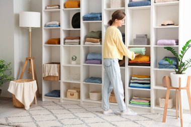 Elbise dolabında kıyafet düzenleyen genç bir kadın.