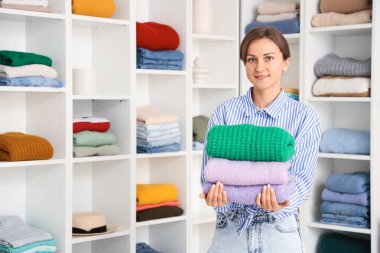 Soyunma odasında bir yığın kalın kazağı olan genç bir kadın.