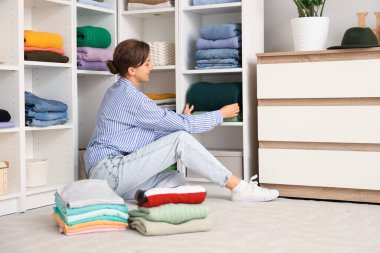 Elbise dolabında kıyafet düzenleyen genç bir kadın.