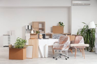 Taşınma gününde masa, kutu ve sandalyelerle dolu bir ofis.