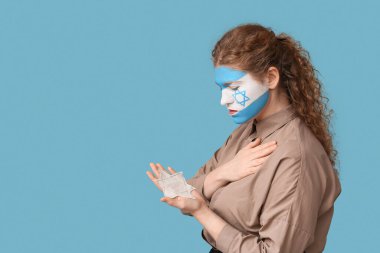 Yüzünde İsrail bayrağı ve mavi arka planda Yahudi rozeti olan genç bir kadın. Uluslararası Soykırım Anma Günü