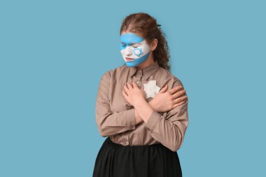 Young woman with painted flag of Israel on her face and Jewish badge against blue background. International Holocaust Remembrance Day clipart