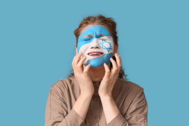 Yüzünde mavi arka planda İsrail bayrağı olan ağlayan genç bir kadın. Uluslararası Soykırım Anma Günü