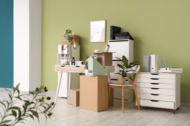 Taşınma gününde iş yerindeki yeşil duvarın yanında su soğutucusu ve karton kutuların olduğu yer.