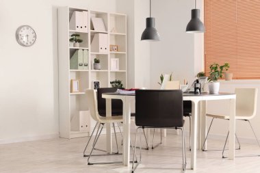 Masası, raf ünitesi ve bitkileri olan ışık ofisinin içinde.