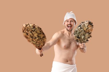 Bej arka planda sauna çırpıcısı olan yakışıklı bir adam.