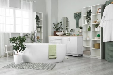 Banyonun içinde küvet, lavabo ve yeşil bitkiler var.