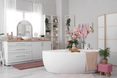 Küveti, lavabosu ve bitkileri olan hafif banyonun içi.