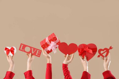 Hediye kutuları ve bej arka planda kalpleri olan kadın elleri. Sevgililer Günü kutlaması