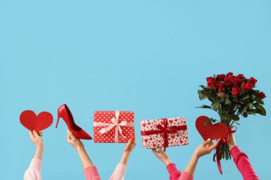 Kalpli kadın elleri, hediye kutuları, yüksek topuklu ayakkabılar ve mavi arka planda güller. Sevgililer Günü kutlaması
