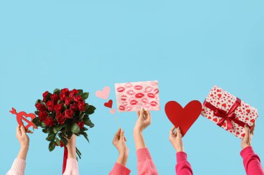 Hediye kutularıyla kadın elleri, mavi arka planda güller ve kalpler. Sevgililer Günü kutlaması