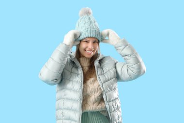 Kış giysileri mavi arka plan üzerinde mutlu genç kadın