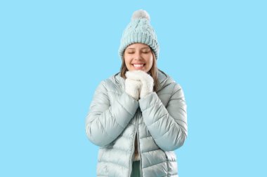 Kış giysileri mavi arka plan üzerinde mutlu genç kadın