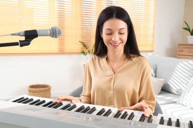 Evde sentezleyici çalan genç bir kadın.