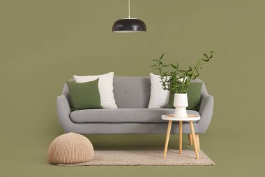 Vazoda bambu saplı masa, kanepe, puf ve lamba yeşil arka planda.