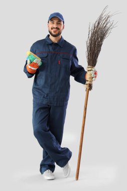 Male scavenger with garbage bags and broom on light background clipart