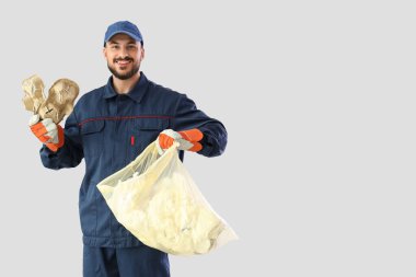 Kağıt çöpü ve açık arkaplanda çantası olan erkek çöpçü.