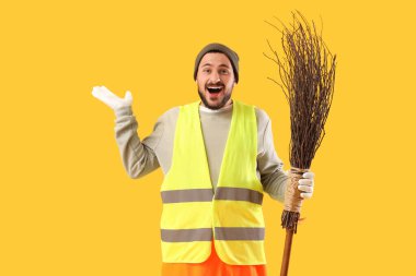 Happy male scavenger with broom on yellow background clipart