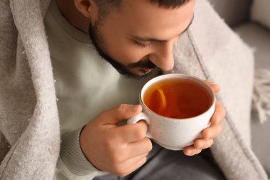 Ekoseli genç adam evde limon çayı içiyor, yakın plan.